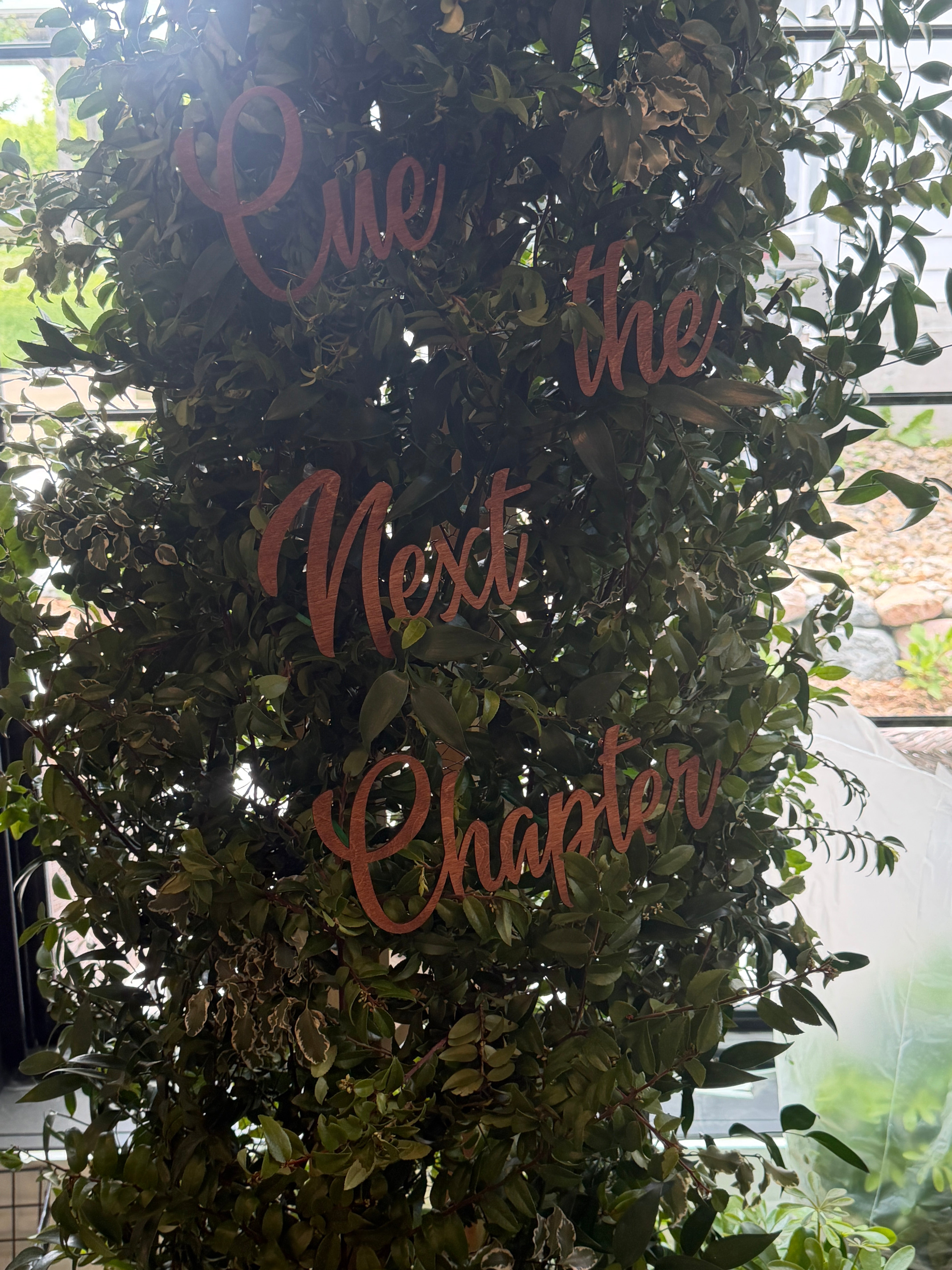 Decorative wreath with 'Cue the Next Chapter' text on a leafy background