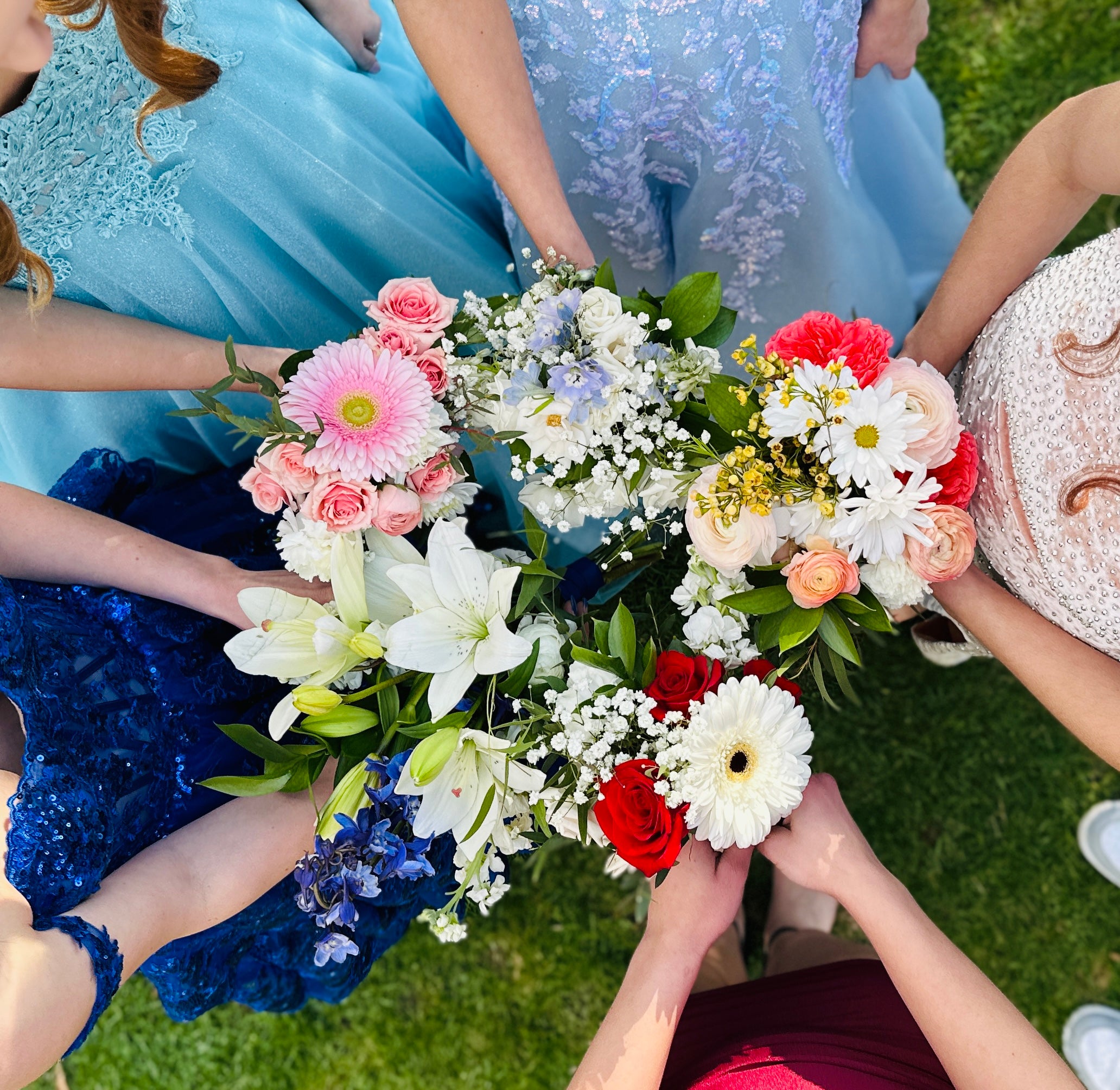 Prom girls holding flower bouquets in a circle on grass