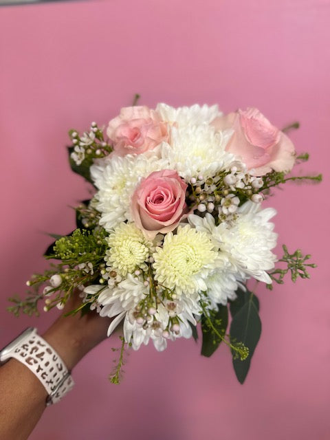 Bouquet of flowers held by a hand against a pink background