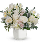 Floral arrangement with white and light pink flowers in a clear vase on a white background