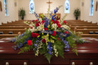 Floral arrangement with red, white, and blue flowers on casket for a funeral service