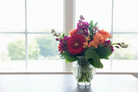 Colorful flower arrangement in a clear vase on a table with a window in the background